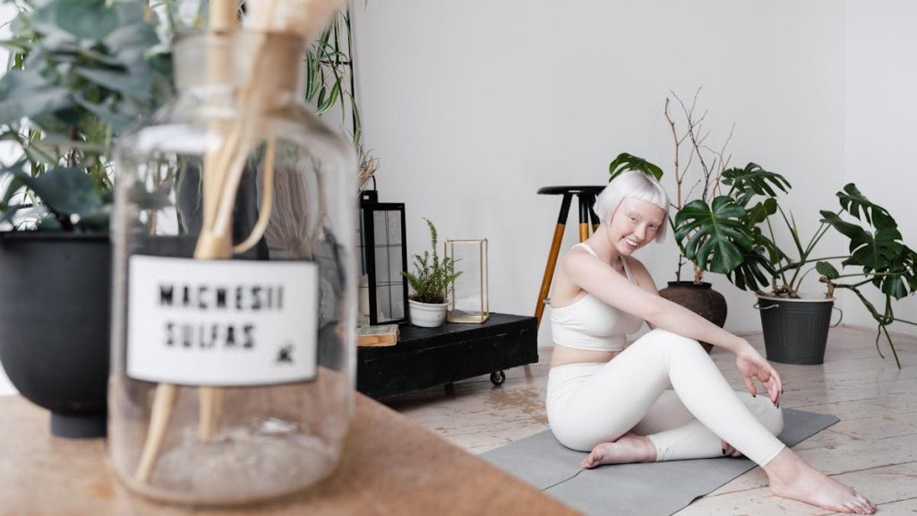 Smiling woman with short white hair practicing yoga indoors surrounded by plants.