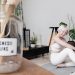 Smiling woman with short white hair practicing yoga indoors surrounded by plants.